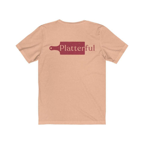 The back of a heather peach colored T-shirt with the Platterful logo in the middle.