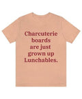 A heather peach colored T-shirt that reads "Charcuterie boards are just grown up Lunchables." in red text.