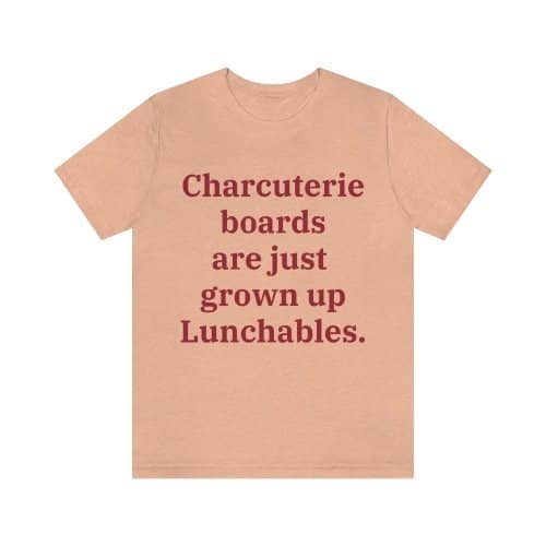 A heather peach colored T-shirt that reads "Charcuterie boards are just grown up Lunchables." in red text.