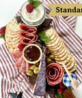 Standard Platterful Charcuterie Kit - Cheese, meat, crackers, spreadables, olives, nuts and chocolates. Everything you need to create the best charcuterie board that is sure to leave your friends and family drooling. Estimated serving size: Small charcuterie board feeds 2-4 as a small appetizer or 1-2 as a meal