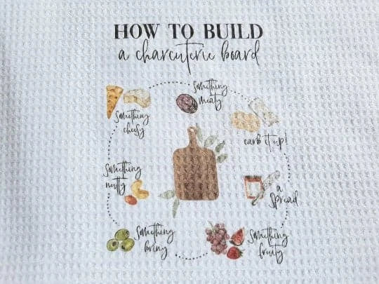 Kitchen towel with instructions on how to build a charcuterie board.